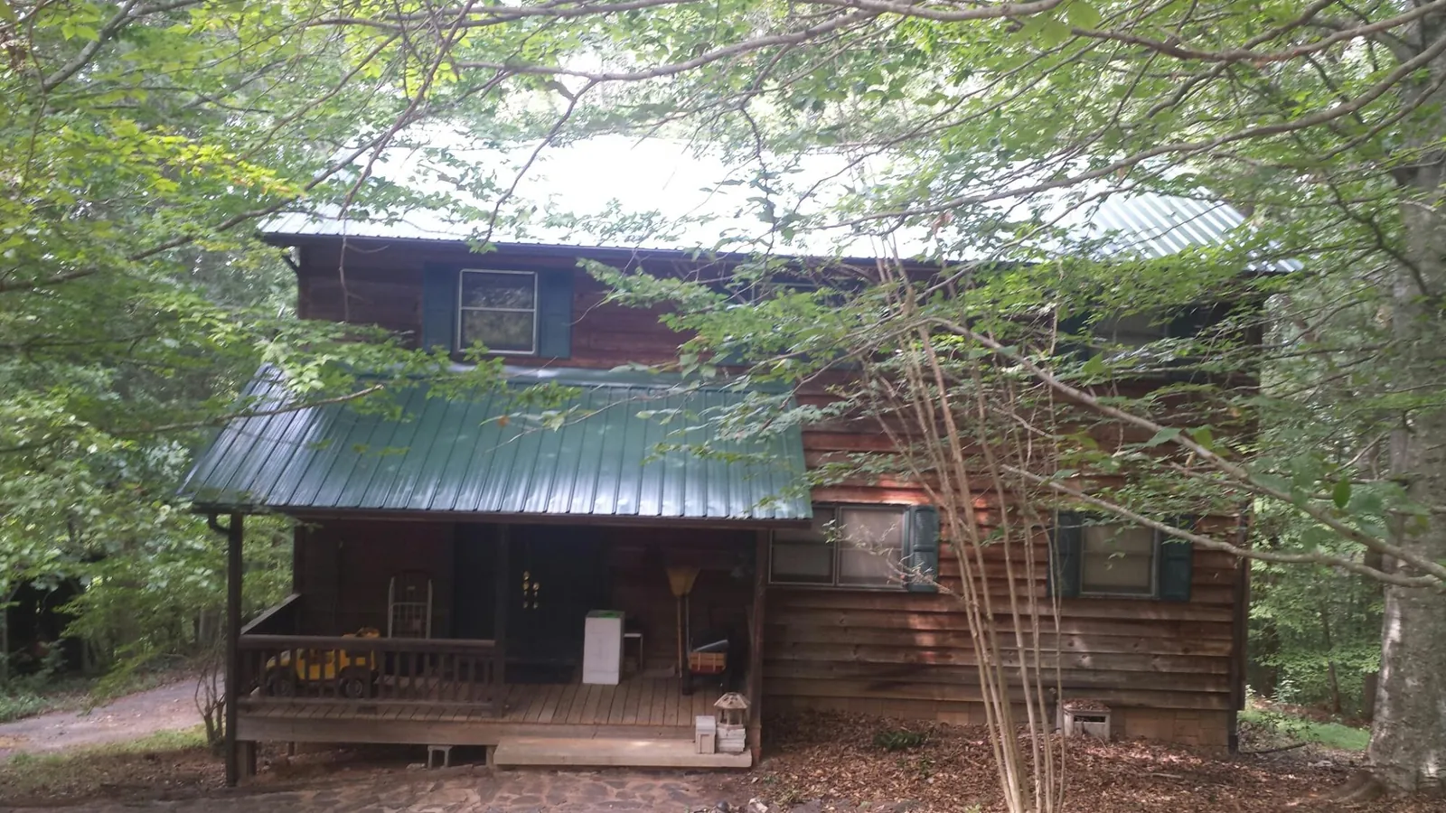 Green metal roof and covered porch on a log cabin in Sebree