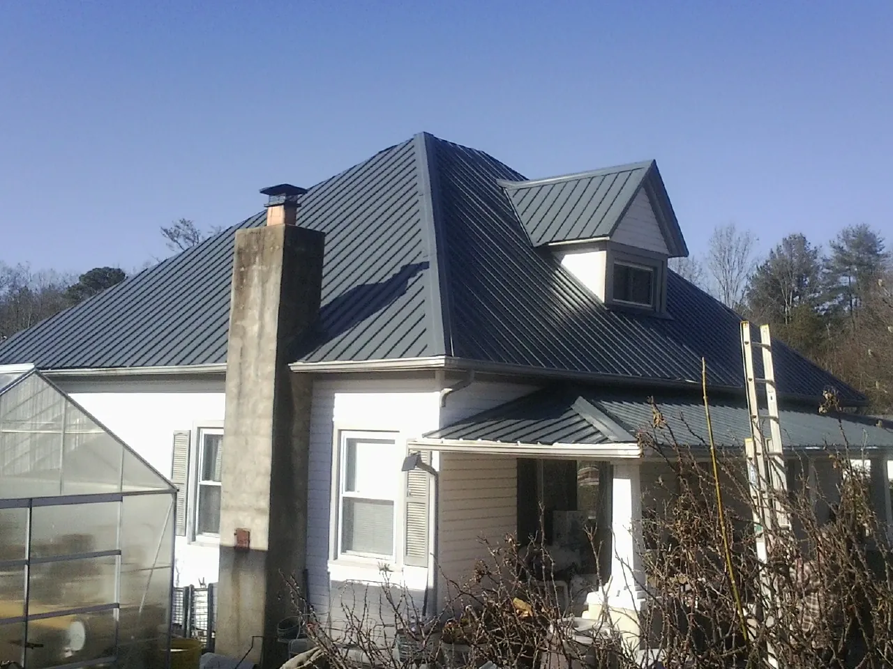 Dark blue standing seam metal roof on a white farmhouse with dormer — Slate & Tile Roof Repair by Roofing Brothers in Sebree