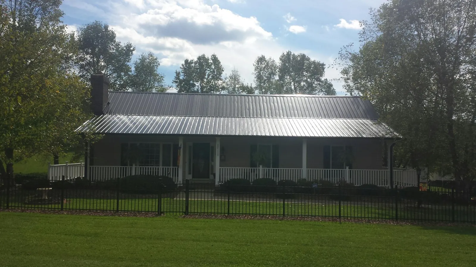 Gray metal roof on a brick ranch with a full width front porch — Gutter Guard Installation work by our crew in Sebree