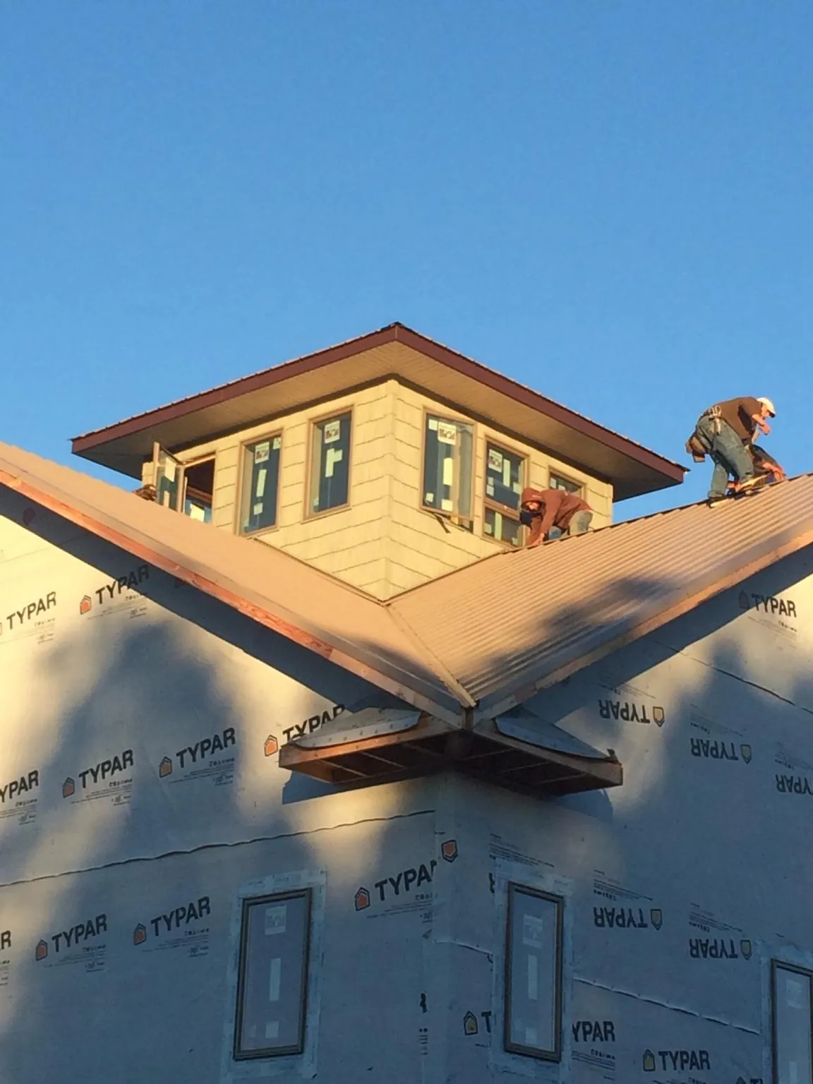 Roofers working around a rooftop cupola on a new metal roof at sunset — Roof Waterproofing in Sebree by Roofing Brothers